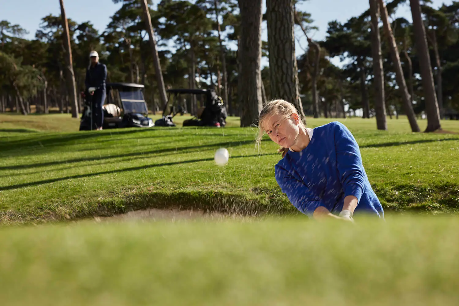 Female golfer practicing bunker shots during a golf tuition lesson at Barsebäck Golf & Country Club in Sweden.